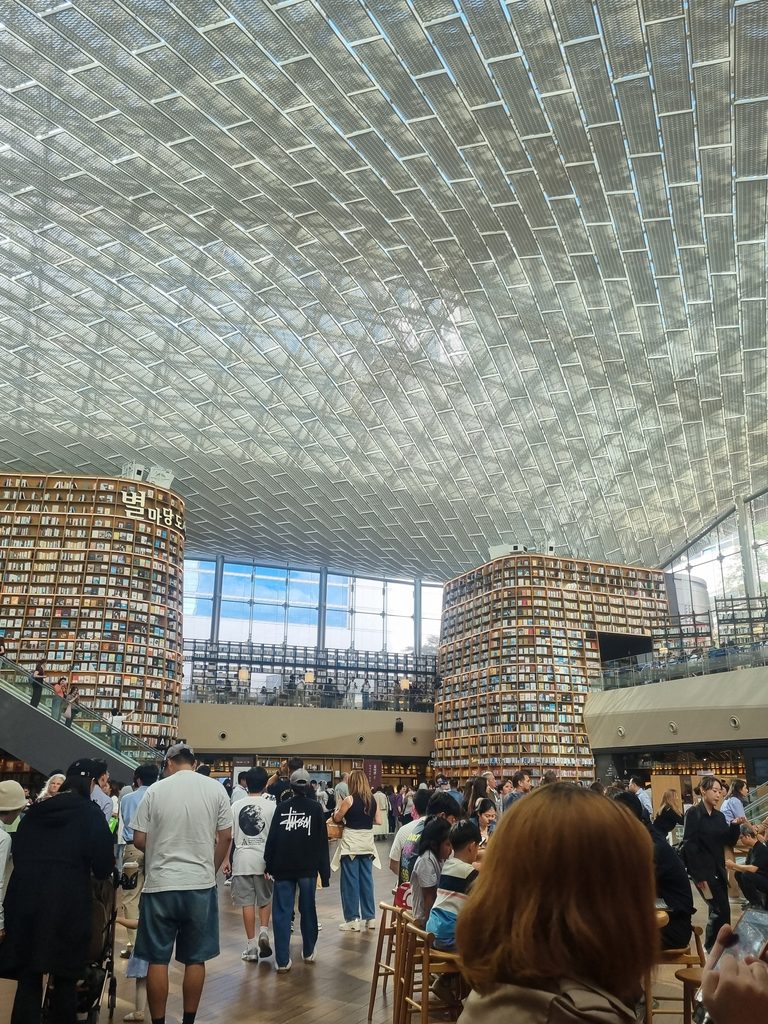 Visitors sitting and taking photographs inside Starfield Library at COEX Mall Seoul
